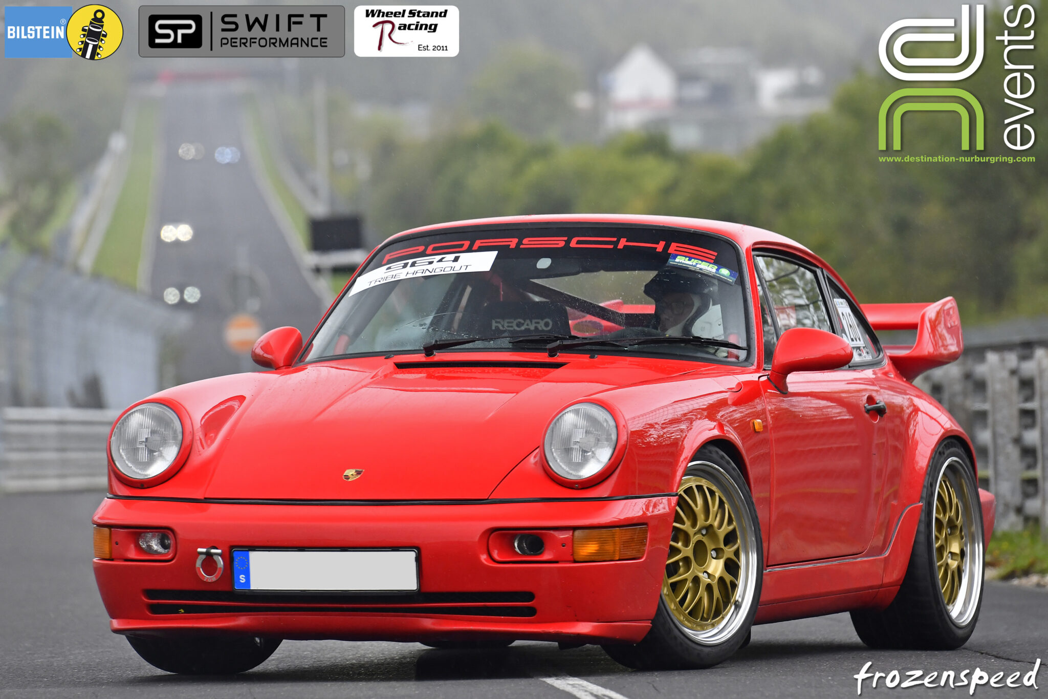 A red Porsche 964 track car leaves the track at the exit point